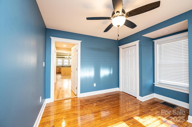 unfurnished bedroom featuring ceiling fan, a closet, and light wood-type flooring