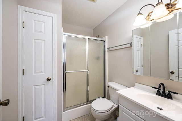 bathroom with a shower with door, vanity, a notable chandelier, and toilet