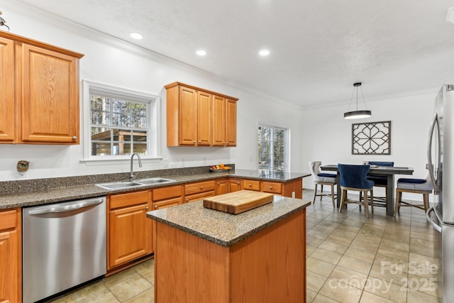 kitchen featuring pendant lighting, sink, appliances with stainless steel finishes, ornamental molding, and a kitchen island