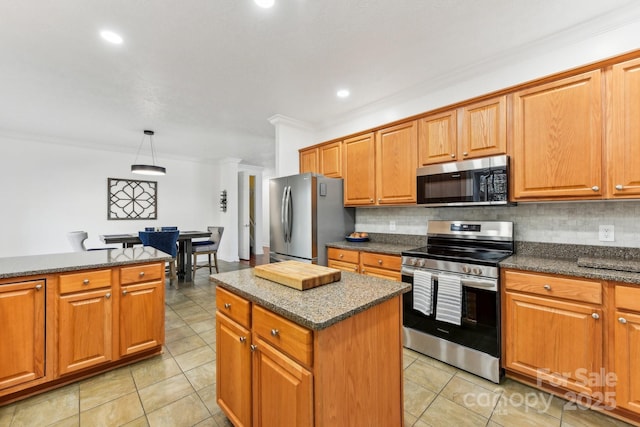 kitchen with a kitchen island, appliances with stainless steel finishes, pendant lighting, and backsplash