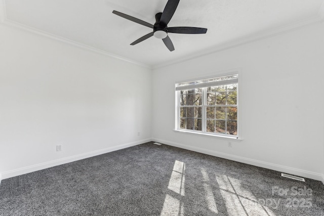 empty room featuring dark colored carpet, ornamental molding, and ceiling fan