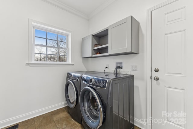 laundry area featuring cabinets, washing machine and clothes dryer, and crown molding