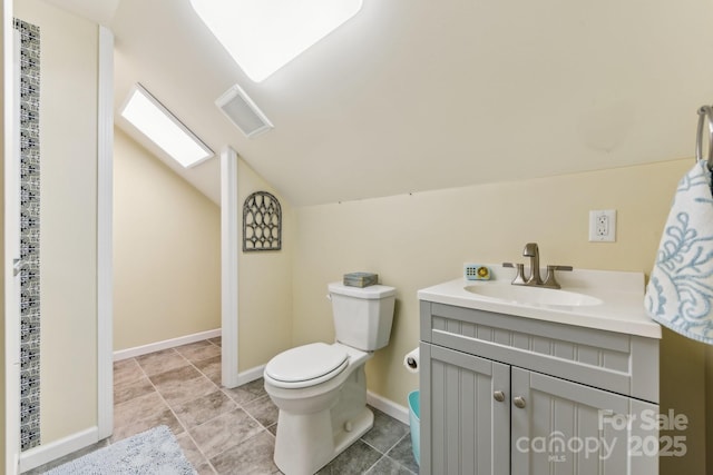 bathroom with vanity, lofted ceiling with skylight, and toilet