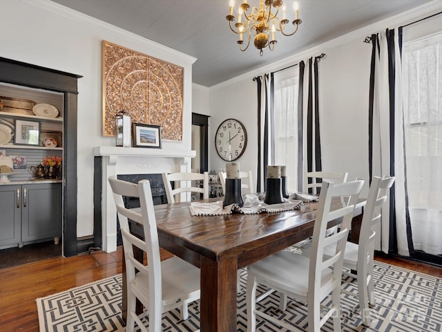 dining area with ornamental molding, a fireplace, an inviting chandelier, and wood finished floors