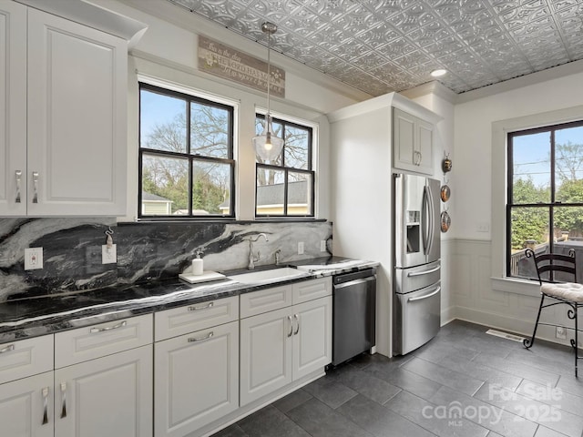 kitchen with a sink, white cabinets, appliances with stainless steel finishes, decorative backsplash, and an ornate ceiling