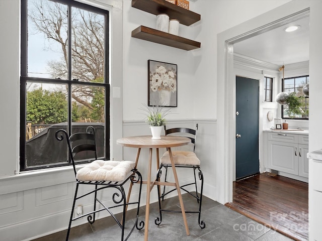 dining space with a wainscoted wall, ornamental molding, a decorative wall, and dark wood finished floors