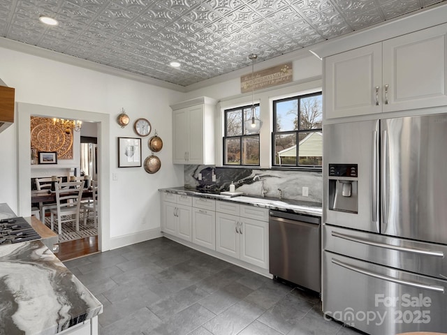 kitchen featuring white cabinets, baseboards, appliances with stainless steel finishes, decorative backsplash, and an ornate ceiling