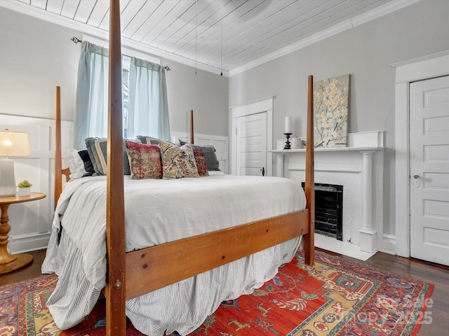 bedroom with wooden ceiling, a fireplace with flush hearth, crown molding, and wood finished floors