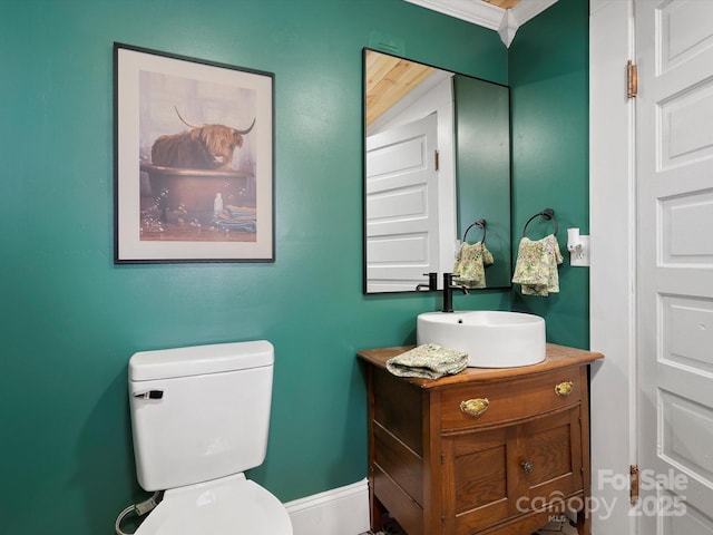 half bath featuring toilet, baseboards, ornamental molding, and vanity