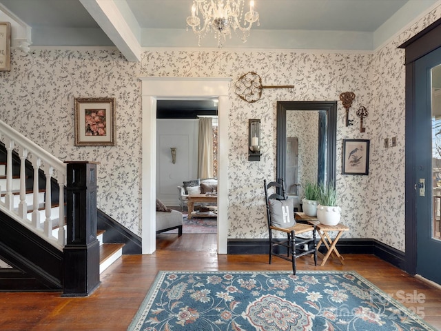 foyer with wallpapered walls, stairway, a chandelier, and wood finished floors