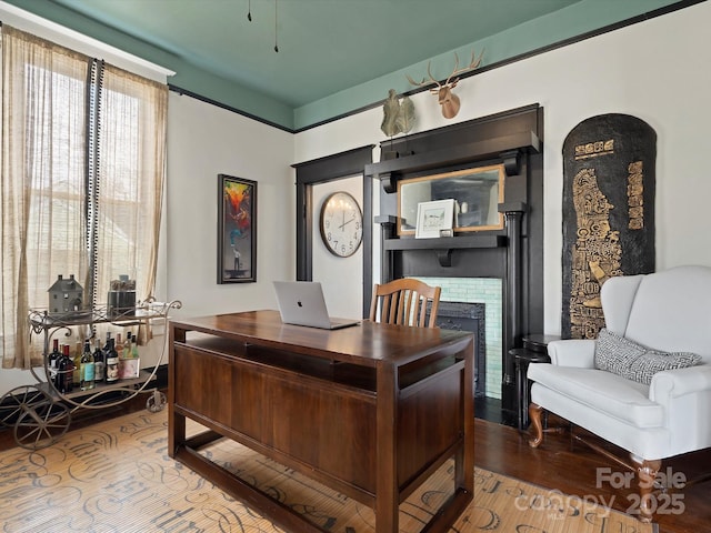 office space with a brick fireplace and wood finished floors