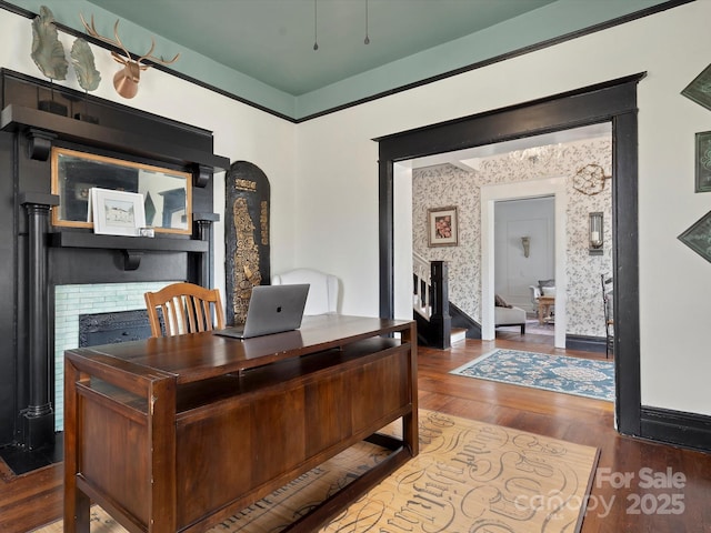 home office with a brick fireplace, wallpapered walls, baseboards, and wood finished floors