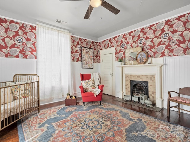 bedroom with wallpapered walls, visible vents, hardwood / wood-style floors, and wainscoting