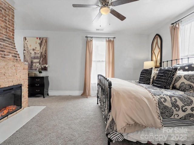 carpeted bedroom featuring a brick fireplace, visible vents, ceiling fan, and baseboards