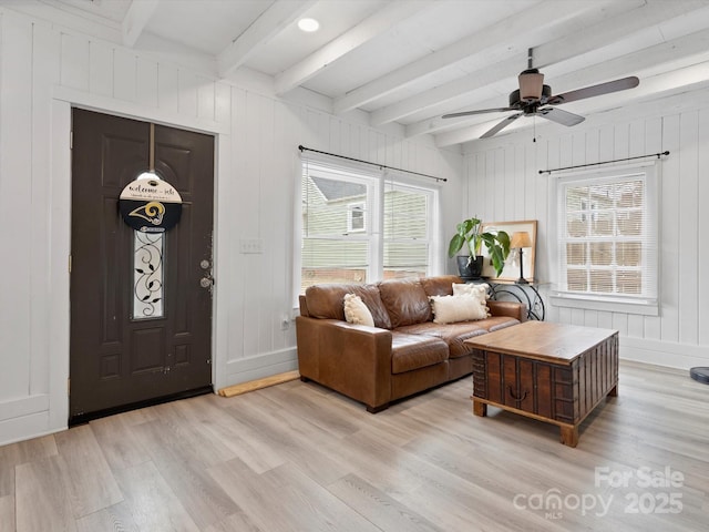 living area with beamed ceiling, light wood-style flooring, baseboards, and ceiling fan