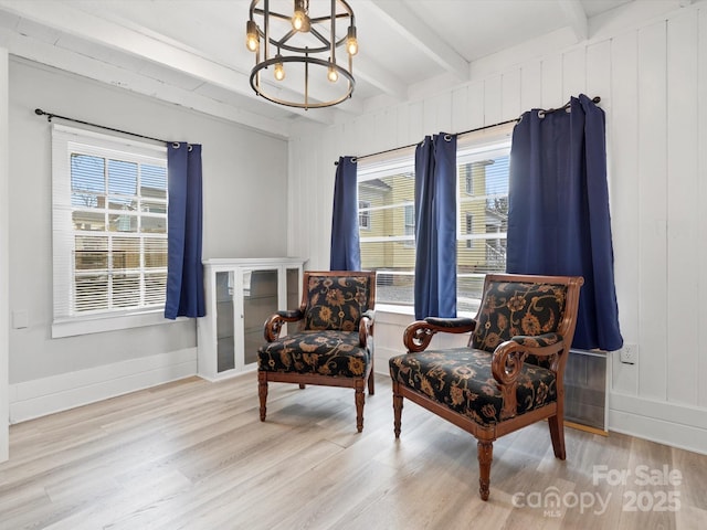 living area with a chandelier, wood finished floors, beam ceiling, and baseboards