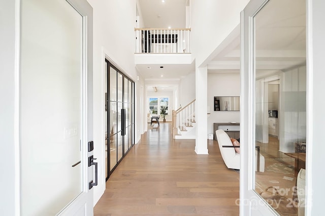 entrance foyer with light hardwood / wood-style floors, french doors, and a high ceiling