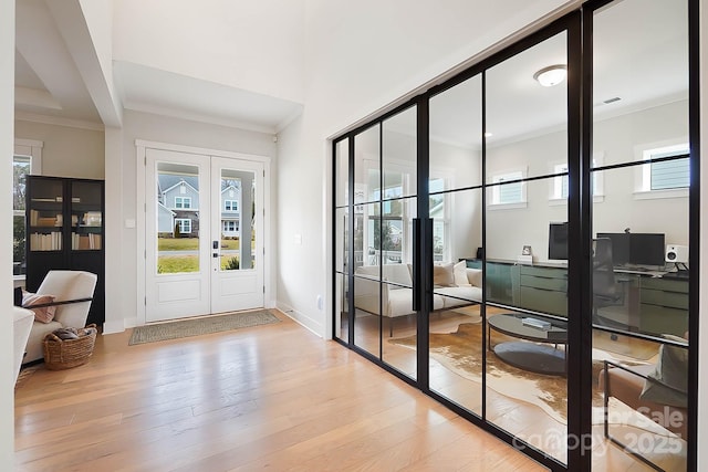 entryway with light hardwood / wood-style flooring, ornamental molding, and french doors