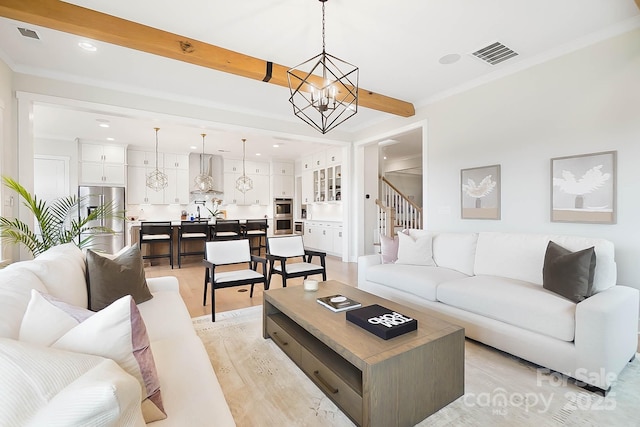 living room with an inviting chandelier, crown molding, light hardwood / wood-style floors, and beamed ceiling