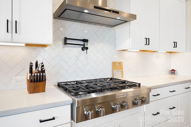 kitchen featuring stainless steel gas stovetop, decorative backsplash, white cabinets, and range hood