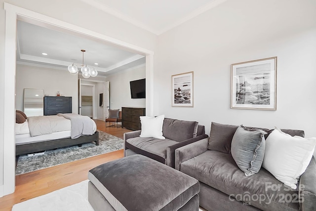 living room featuring a raised ceiling, crown molding, hardwood / wood-style floors, and an inviting chandelier