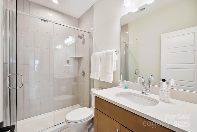 bathroom featuring vanity, toilet, and a shower with shower door