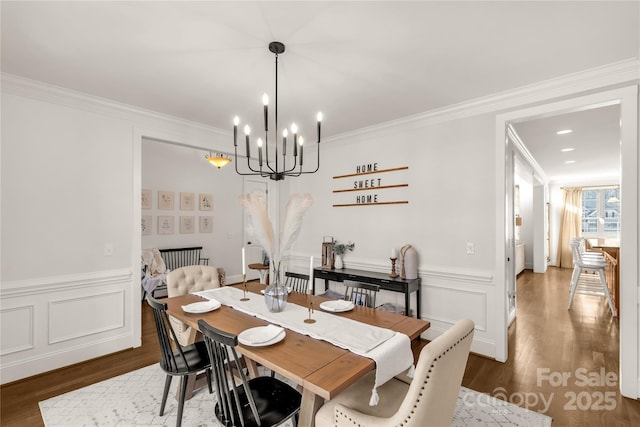 dining space with ornamental molding, an inviting chandelier, and dark hardwood / wood-style flooring