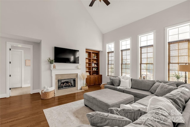 living room featuring dark hardwood / wood-style flooring, high vaulted ceiling, and ceiling fan