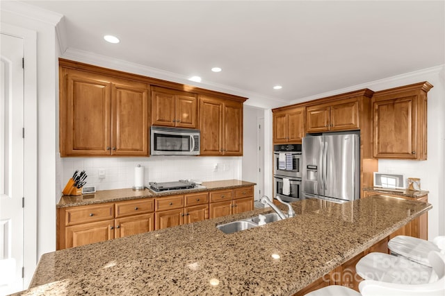 kitchen featuring appliances with stainless steel finishes, a breakfast bar, sink, and light stone countertops