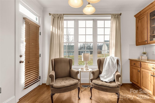 sitting room with light hardwood / wood-style flooring and ornamental molding