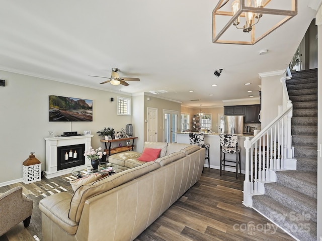 living room with crown molding, ceiling fan with notable chandelier, and dark hardwood / wood-style flooring