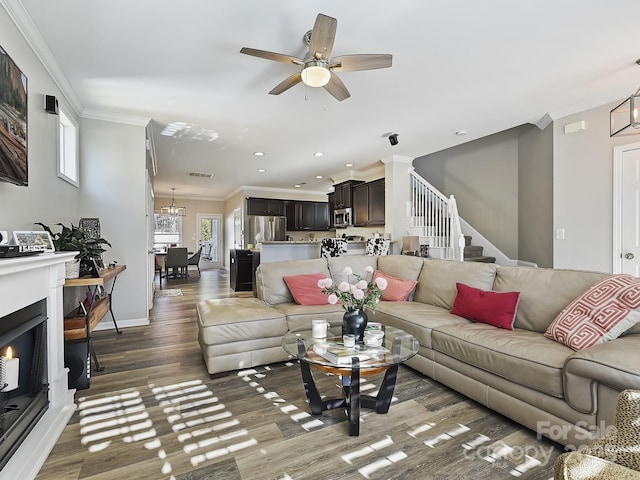 living room featuring ceiling fan with notable chandelier, ornamental molding, and dark hardwood / wood-style floors