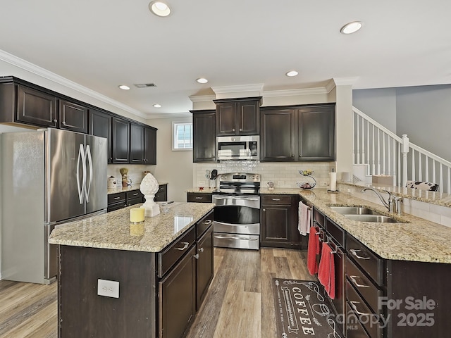 kitchen with sink, crown molding, stainless steel appliances, light hardwood / wood-style floors, and decorative backsplash