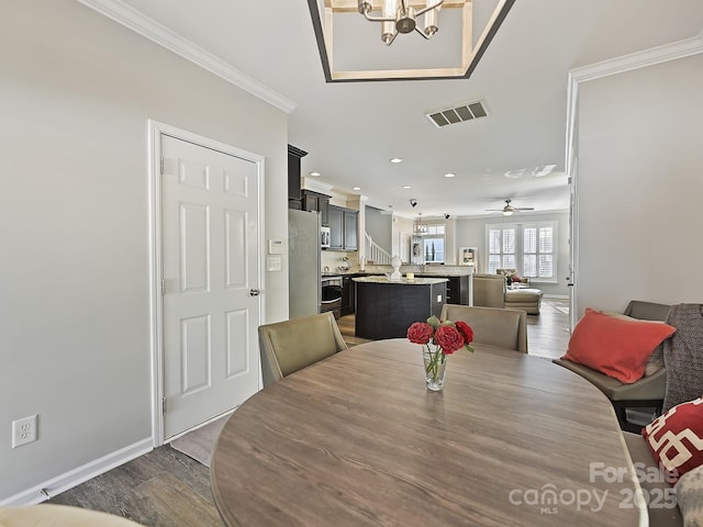 dining space featuring crown molding, dark hardwood / wood-style floors, and ceiling fan with notable chandelier