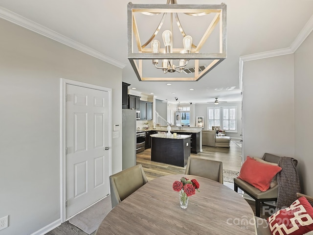 dining area featuring hardwood / wood-style floors, ceiling fan with notable chandelier, and ornamental molding