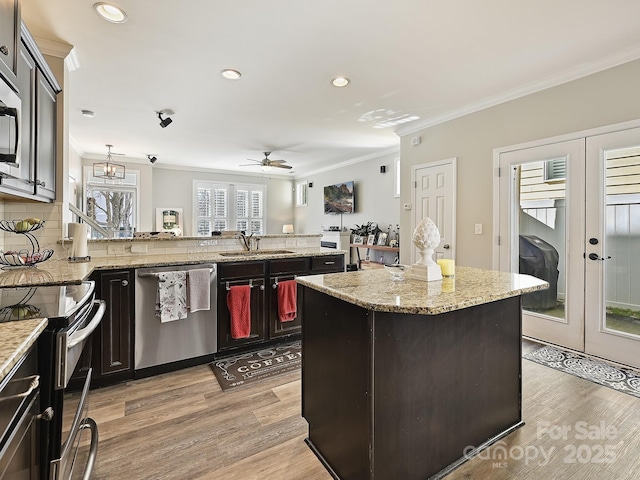 kitchen featuring french doors, stainless steel appliances, a center island, and light stone countertops