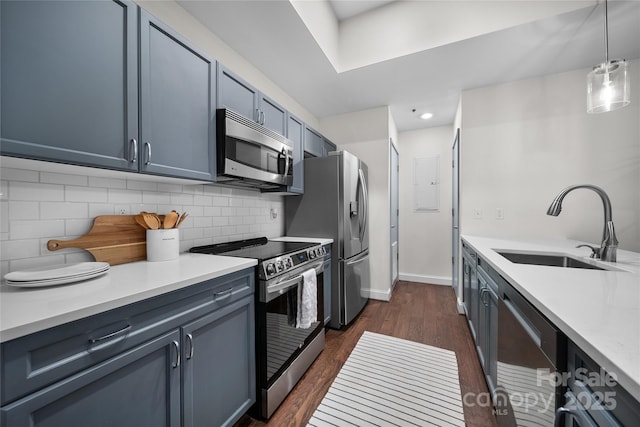 kitchen featuring appliances with stainless steel finishes, dark hardwood / wood-style floors, decorative light fixtures, sink, and decorative backsplash