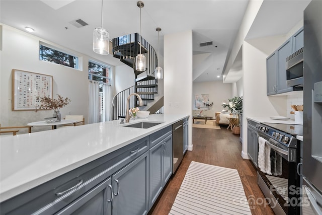 kitchen featuring stainless steel appliances, sink, gray cabinetry, and decorative light fixtures