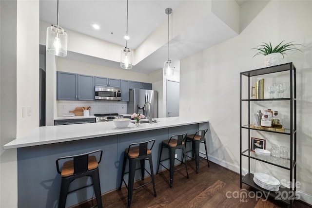 kitchen featuring pendant lighting, blue cabinets, a kitchen breakfast bar, and appliances with stainless steel finishes