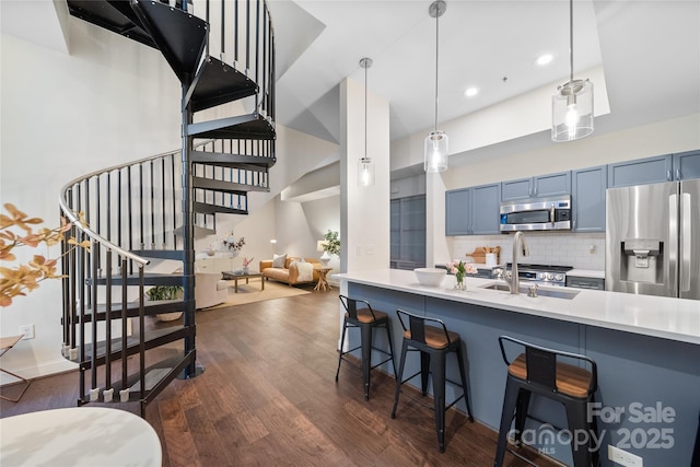 kitchen featuring blue cabinetry, stainless steel appliances, a breakfast bar area, and pendant lighting