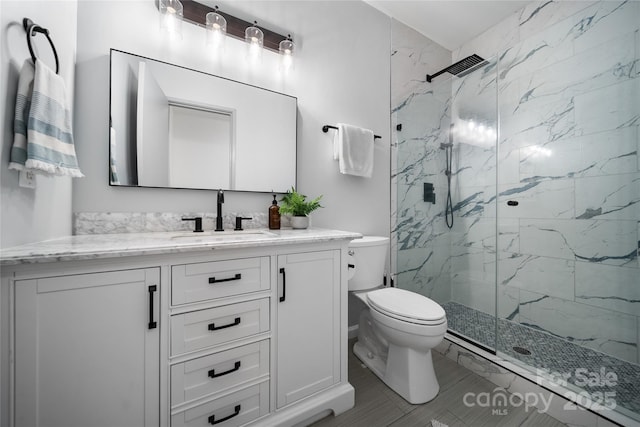 bathroom with a shower with door, vanity, and toilet