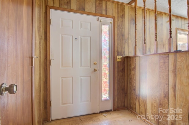 entryway featuring light wood-type flooring and wooden walls