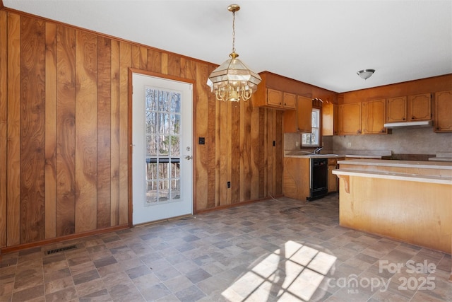 kitchen with pendant lighting, wooden walls, dishwasher, backsplash, and a chandelier