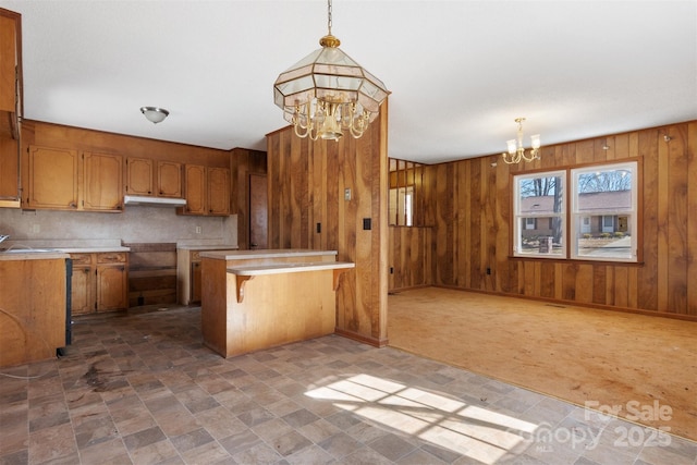 kitchen featuring pendant lighting, a kitchen breakfast bar, wood walls, and an inviting chandelier