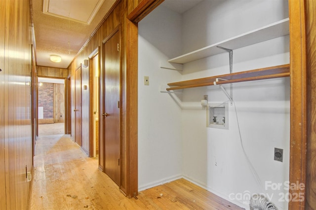 laundry room with light hardwood / wood-style floors, hookup for a washing machine, and wood walls