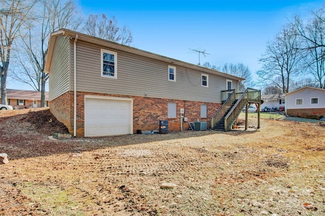 rear view of property with a garage and central AC