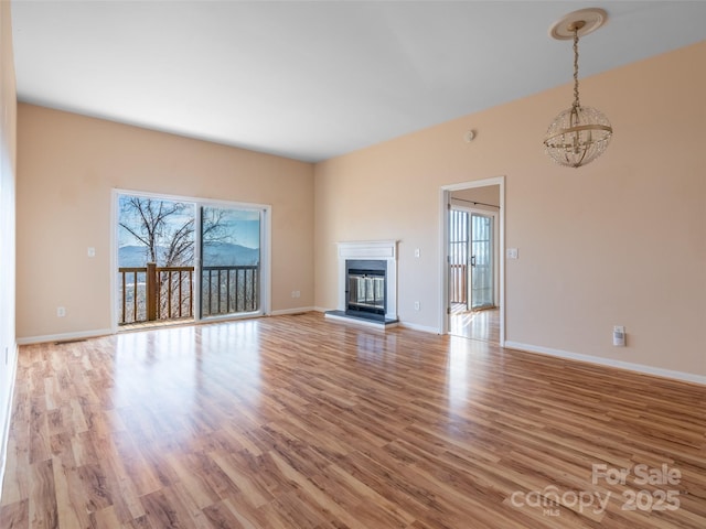 unfurnished living room featuring a chandelier and light hardwood / wood-style floors