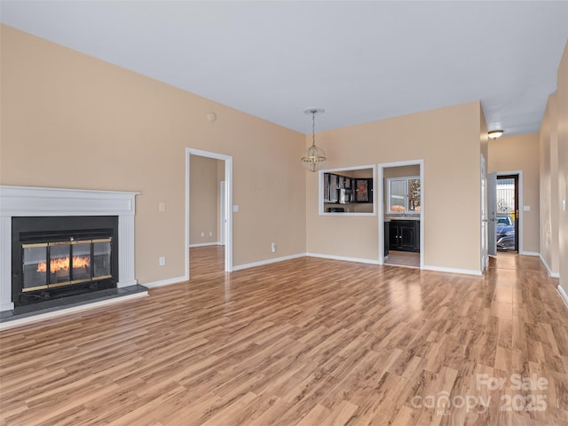 unfurnished living room featuring a chandelier and light hardwood / wood-style flooring