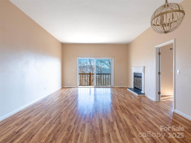 unfurnished living room featuring an inviting chandelier and light hardwood / wood-style floors