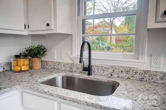 details with white cabinetry, sink, and light stone counters